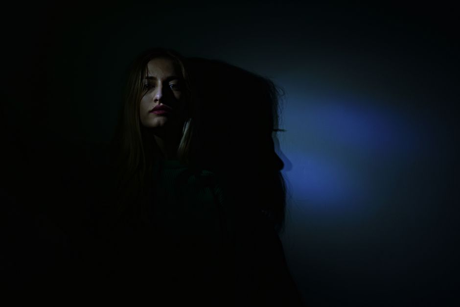 A dark, mysterious portrait highlighting shadows cast by a woman's face.